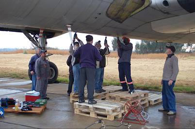 A group of men working on a plane

Description automatically generated