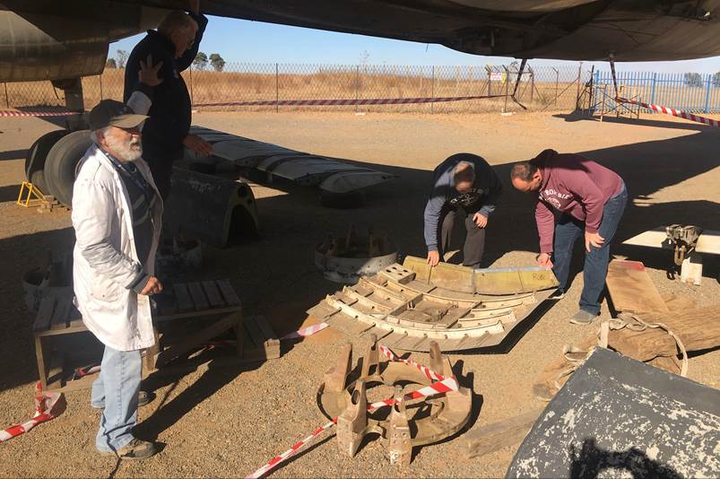 A group of men looking at a piece of wood

Description automatically generated