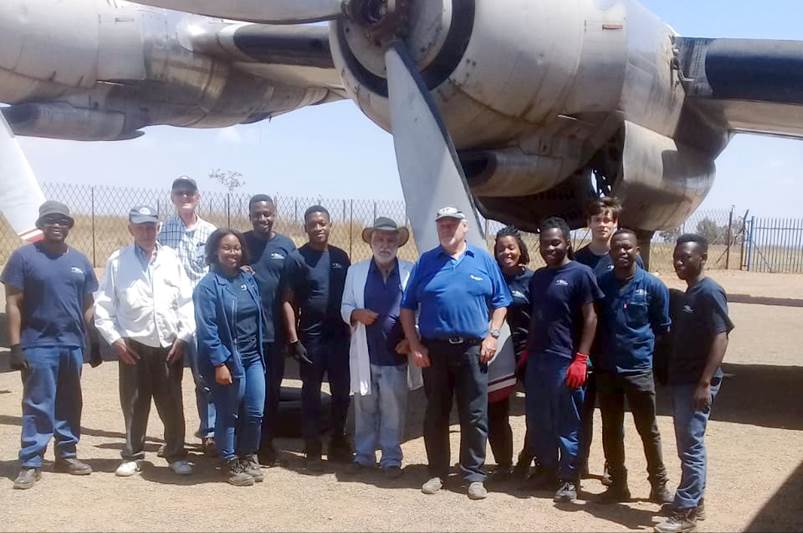 A group of people standing in front of an airplane

Description automatically generated