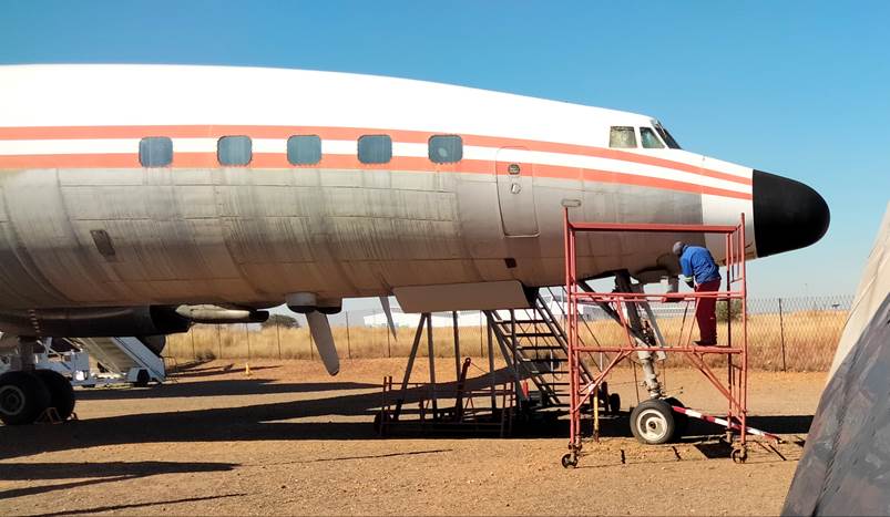 A plane parked on a dirt field

Description automatically generated