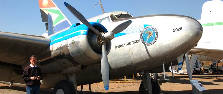 A person standing next to a propeller plane

Description automatically generated