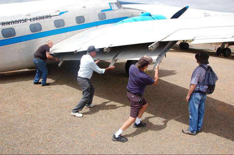 Men pushing the wing of an airplane

Description automatically generated