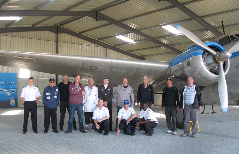 A group of people posing in a hangar

Description automatically generated