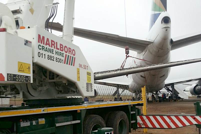 A large white airplane being loaded onto a truck

Description automatically generated