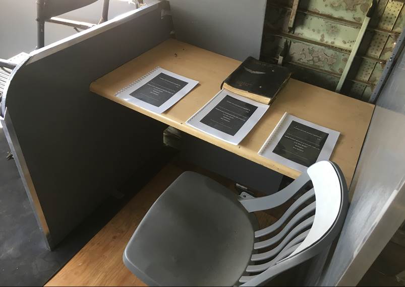 A chair and a table with papers on it

Description automatically generated