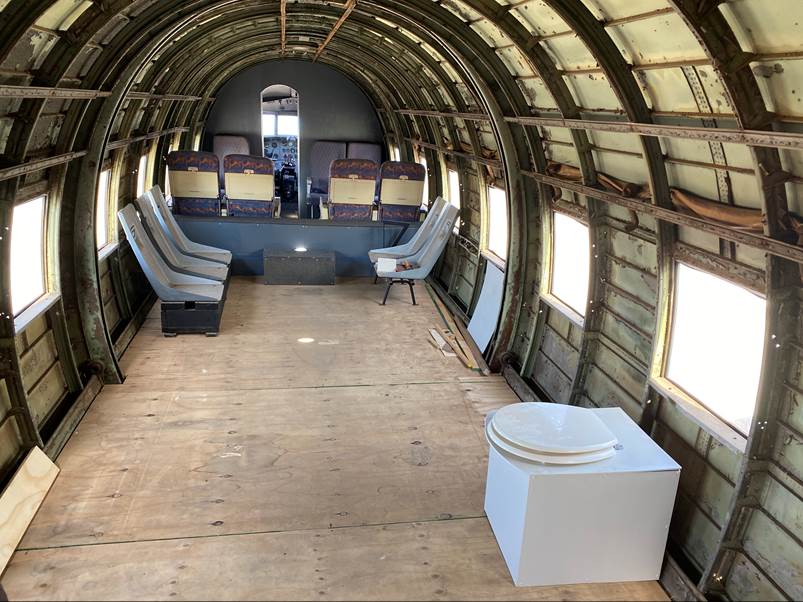 Inside a plane with chairs and a toilet

Description automatically generated with medium confidence