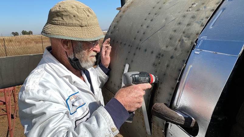 A person using a drill to fix a piece of metal

Description automatically generated