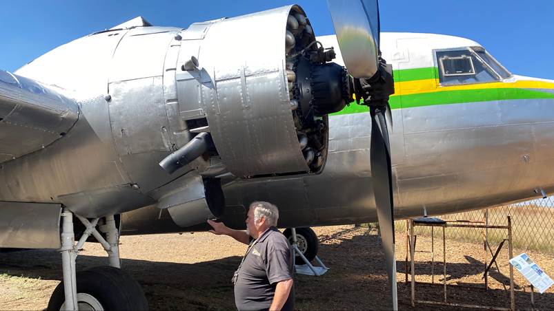 A person standing next to a propeller plane

Description automatically generated