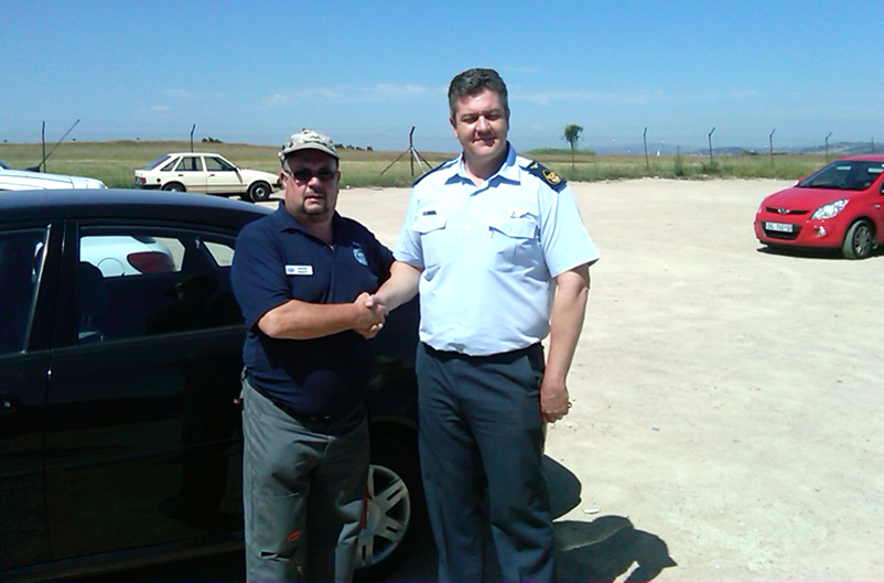 A person standing in front of a car posing for the camera

Description automatically generated