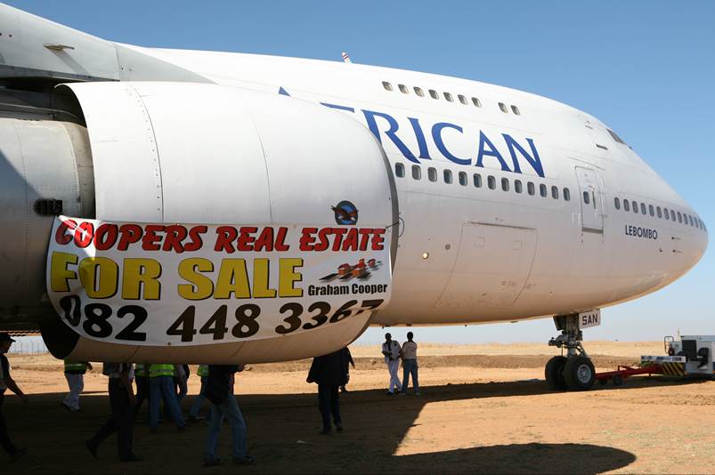 A large white airplane with advertisement on the side

Description automatically generated