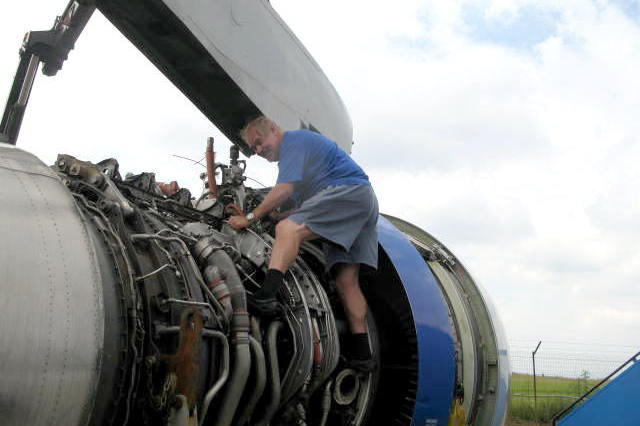 A person working on an airplane engine

Description automatically generated