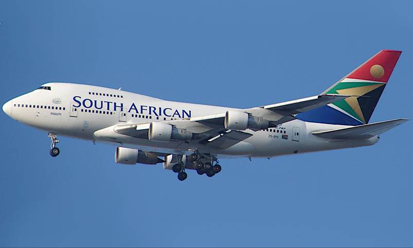 A large passenger jet flying through a blue sky

Description automatically generated