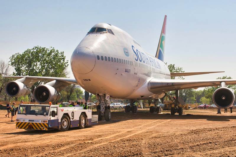 A large airplane on a dirt field

Description automatically generated