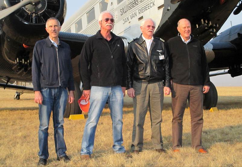 A group of men standing in front of an airplane

Description automatically generated