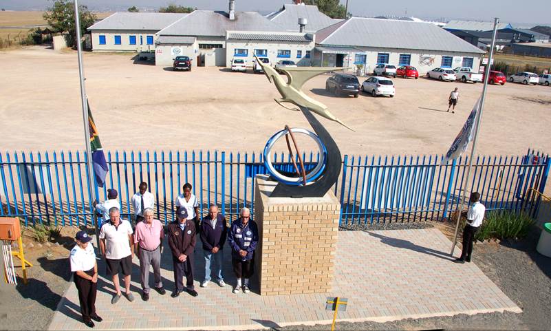 A group of people standing in front of a blue fence

Description automatically generated