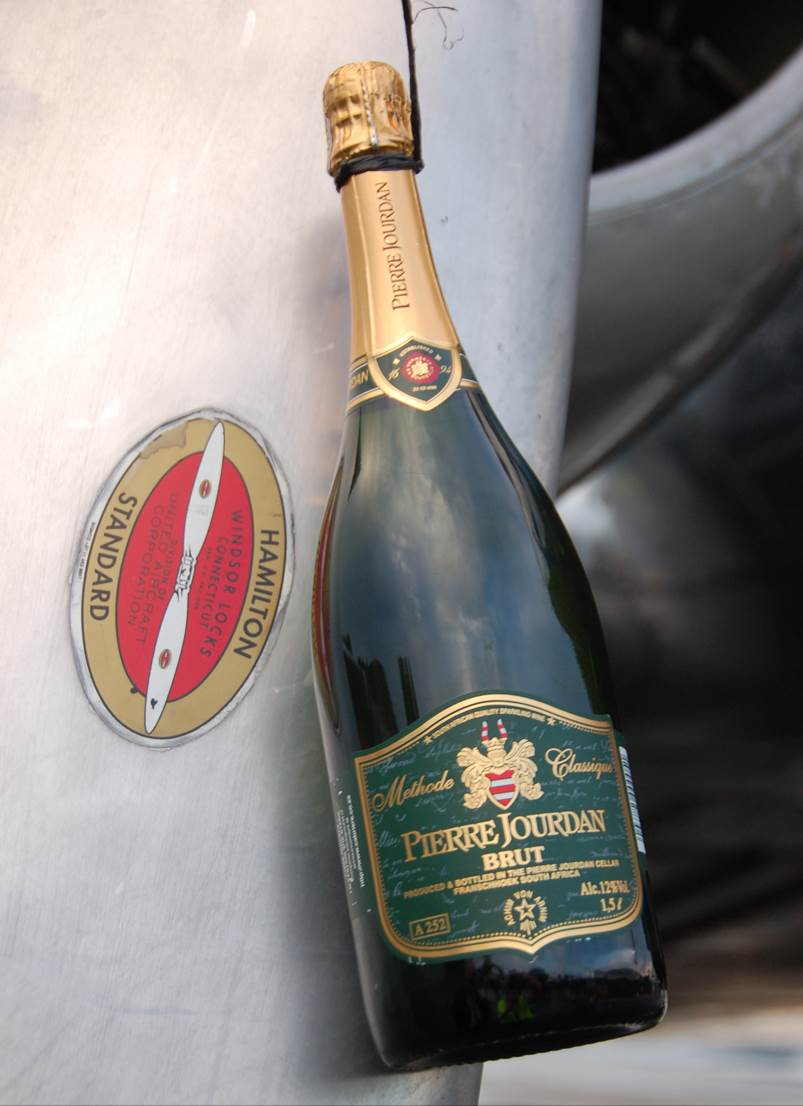 A bottle of champagne next to a metal barrel

Description automatically generated